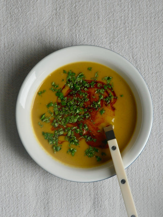 Potage crémeux à la courge musquée et au beurre de cajou, garni de coriandre fraîche et de chili crisp